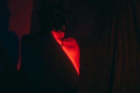 Geste de soin entre deux participant·es d'une soirée BDSM, dans la lumière rouge