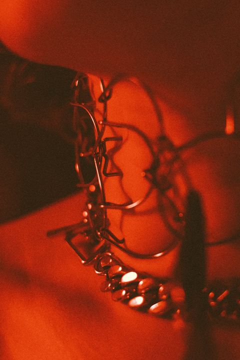 Collier de cuir et chaîne portés lors d'une soirée femdom, sous la lumière rouge