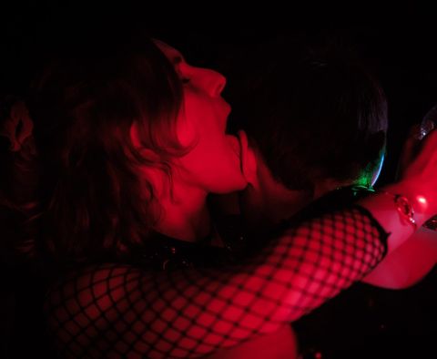 Deux personnes enlacées sous la lumière rouge d'une soirée sexpositive de L'Obsidienne